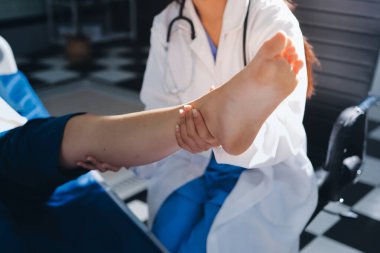 Kadın doktor elleri, erkek bir hastanın bacağını ve dizini uzatarak fizik tedavi uyguluyor.