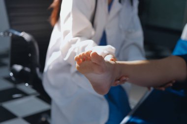 Kadın doktor elleri, erkek bir hastanın bacağını ve dizini uzatarak fizik tedavi uyguluyor.