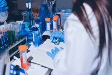 Bilimadamı laboratuarda tıbbi örnekleri mikro plakaya yerleştiriyor.