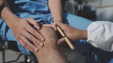 Doktor hasta bir adamın ayağını kontrol ediyor.