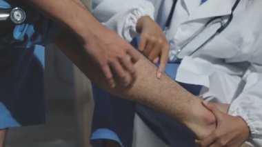 Doktor klinikte hasta bacağını muayene ediyor.