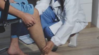 Erkek fizyoterapist hastasını muayenehanede bacağına veriyor..