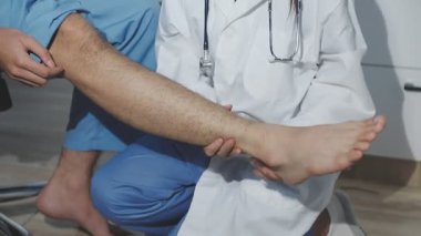 Doktor ofiste bacak masajı yapıyor.