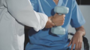 Genç erkek terapist halterlerle fiziksel egzersiz yapıyor..