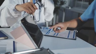 Üniformalı ve steteskoplu bir doktor bir şeyi tartışıyor.