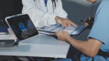 Kadın doktor tablet bilgisayarı tutuyor ve klinikteki kamerayı işaret ediyor..