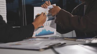 İşadamı ofisteki belgede grafiğe işaret ediyor.