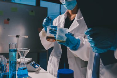 Bilimadamı laboratuarda tıbbi örnekleri mikro plakaya yerleştiriyor.