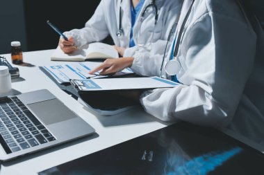 Erkek ve kadın doktorlar bir hastane odasında toplantı yapıyorlar..