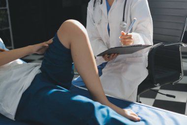 Kadın doktor elleri, erkek bir hastanın bacağını ve dizini uzatarak fizik tedavi uyguluyor.