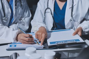 Erkek ve kadın doktorlar bir hastane odasında toplantı yapıyorlar..