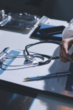 Konuşurken kalp atışı ve semptomlarını incelemek için steteskop kullanan erkek doktorun el görüntüsü.