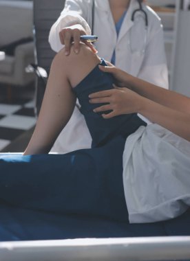 Kadın doktor elleri, erkek bir hastanın bacağını ve dizini uzatarak fizik tedavi uyguluyor.