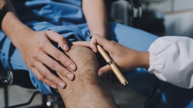 Hastanedeki hastaya diz masajı yaparken doktorların ellerini kapat.
