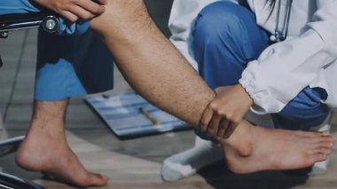 Doktor, bacağı klinikte olan hastayı muayene ediyor.