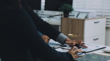 Takım elbiseli kadın avukat, elinde terazi ve kalemle müvekkilinin yanında.