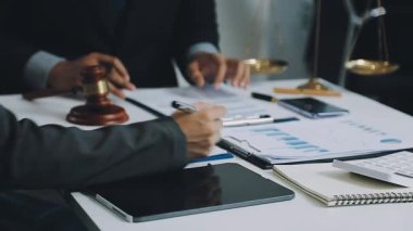 Takım elbiseli ve kravatlı işadamı masada dizüstü bilgisayar ve belgelerle oturuyor..