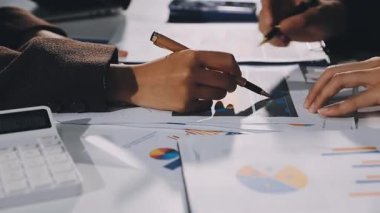 İş adamları mali belgeler üzerinde çalışıyor ve iş yerinde dizüstü bilgisayar ve grafikle yeni iş projelerini tartışıyorlar