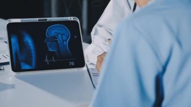 Beyaz önlüklü kadın hasta, elinde röntgen filmi var.