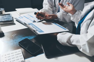 Erkek ve kadın doktorlar bir hastane odasında toplantı yapıyorlar..