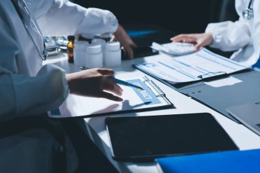 Erkek ve kadın doktorlar bir hastane odasında toplantı yapıyorlar..