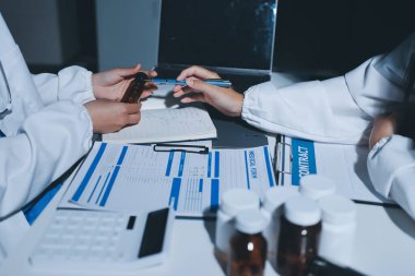 Erkek ve kadın doktorlar bir hastane odasında toplantı yapıyorlar..