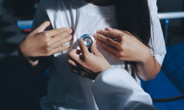 Konuşurken kalp atışı ve semptomlarını incelemek için steteskop kullanan erkek doktorun el görüntüsü.