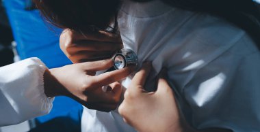 Konuşurken kalp atışı ve semptomlarını incelemek için steteskop kullanan erkek doktorun el görüntüsü.