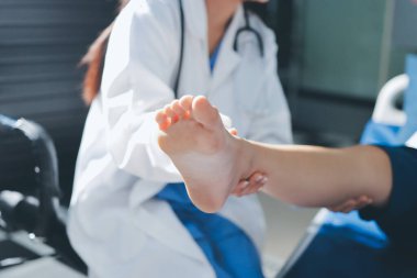 Kadın doktor elleri, erkek bir hastanın bacağını ve dizini uzatarak fizik tedavi uyguluyor.