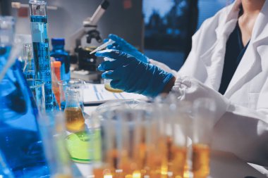 Bilimadamı laboratuarda tıbbi örnekleri mikro plakaya yerleştiriyor.