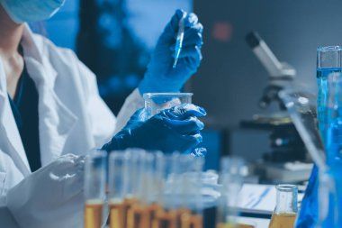 Bilimadamı laboratuarda tıbbi örnekleri mikro plakaya yerleştiriyor.