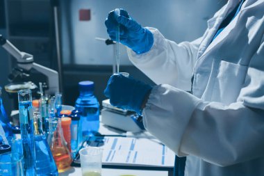 Bilimadamı laboratuarda tıbbi örnekleri mikro plakaya yerleştiriyor.