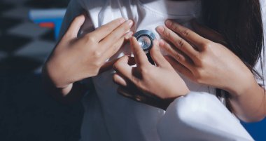 Konuşurken kalp atışı ve semptomlarını incelemek için steteskop kullanan erkek doktorun el görüntüsü.