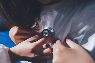 Konuşurken kalp atışı ve semptomlarını incelemek için steteskop kullanan erkek doktorun el görüntüsü.