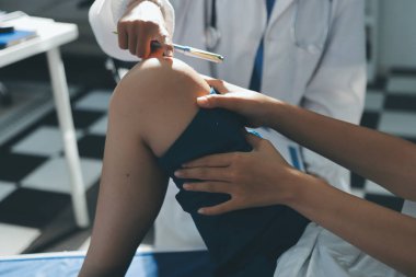 Kadın doktor elleri, erkek bir hastanın bacağını ve dizini uzatarak fizik tedavi uyguluyor.