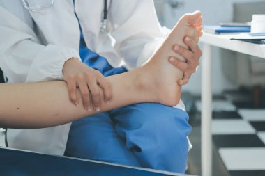 Kadın doktor elleri, erkek bir hastanın bacağını ve dizini uzatarak fizik tedavi uyguluyor.