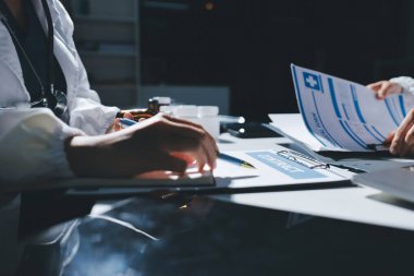 Erkek ve kadın doktorlar bir hastane odasında toplantı yapıyorlar..