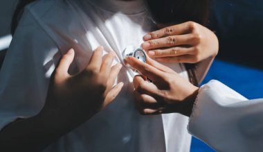 Konuşurken kalp atışı ve semptomlarını incelemek için steteskop kullanan erkek doktorun el görüntüsü.