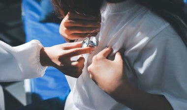 Konuşurken kalp atışı ve semptomlarını incelemek için steteskop kullanan erkek doktorun el görüntüsü.