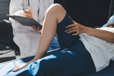 Kadın doktor elleri, erkek bir hastanın bacağını ve dizini uzatarak fizik tedavi uyguluyor.