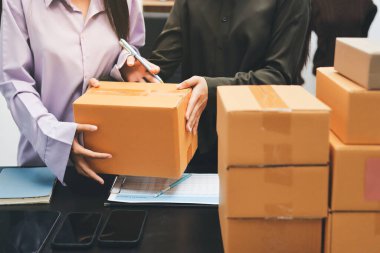 Küçük işletmeler kurma portresi KOBİ sahipleri ve iki Asyalı kadın online siparişleri kontrol ediyor. Ev işlerinde çalışan kutucuklarla çalışan ürünleri satıyorlar.