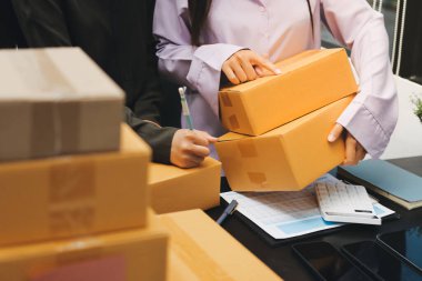Küçük işletmeler kurma portresi KOBİ sahipleri ve iki Asyalı kadın online siparişleri kontrol ediyor. Ev işlerinde çalışan kutucuklarla çalışan ürünleri satıyorlar.