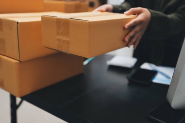 Küçük işletmeler kurma portresi KOBİ sahipleri ve iki Asyalı kadın online siparişleri kontrol ediyor. Ev işlerinde çalışan kutucuklarla çalışan ürünleri satıyorlar.