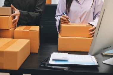 Küçük işletmeler kurma portresi KOBİ sahipleri ve iki Asyalı kadın online siparişleri kontrol ediyor. Ev işlerinde çalışan kutucuklarla çalışan ürünleri satıyorlar.