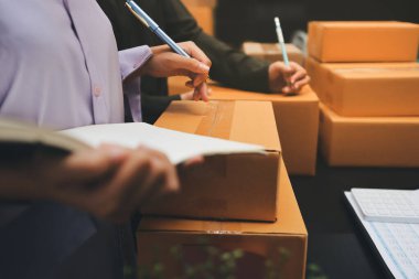 Küçük işletmeler kurma portresi KOBİ sahipleri ve iki Asyalı kadın online siparişleri kontrol ediyor. Ev işlerinde çalışan kutucuklarla çalışan ürünleri satıyorlar.