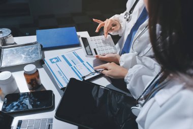 Erkek ve kadın doktorlar bir hastane odasında toplantı yapıyorlar..