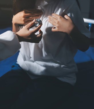 Konuşurken kalp atışı ve semptomlarını incelemek için steteskop kullanan erkek doktorun el görüntüsü.