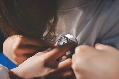 Konuşurken kalp atışı ve semptomlarını incelemek için steteskop kullanan erkek doktorun el görüntüsü.