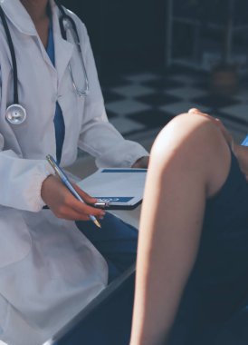 Kadın doktor elleri, erkek bir hastanın bacağını ve dizini uzatarak fizik tedavi uyguluyor.