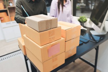 Küçük işletmeler kurma portresi KOBİ sahipleri ve iki Asyalı kadın online siparişleri kontrol ediyor. Ev işlerinde çalışan kutucuklarla çalışan ürünleri satıyorlar.